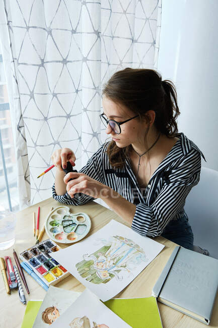 Тисячолітня дівчинка малює чудові зображення на папері, сидячи вдома. — стокове фото