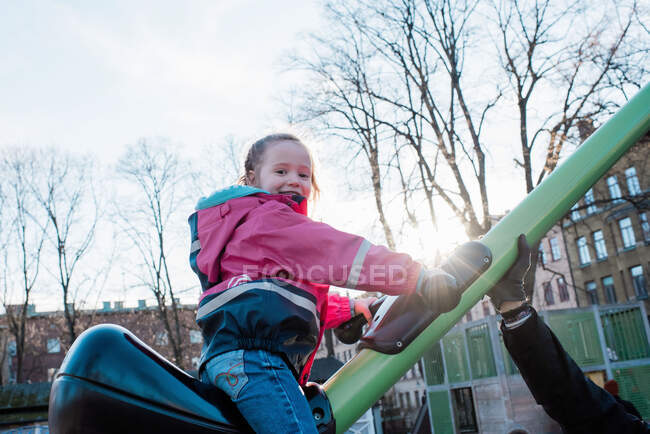 Niña jugando en un parque en Suecia al atardecer con su padre - foto de stock