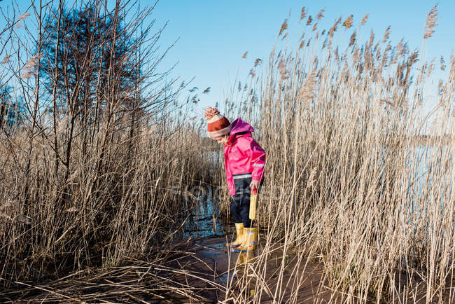 Young girl playing in long grass by the beach in winter — Stock Photo