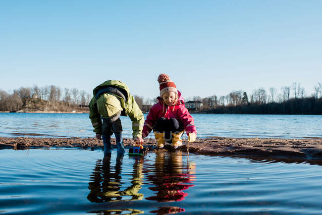 Geschwister spielen zusammen an einem sonnigen Strand im Winter in Schweden — Stockfoto