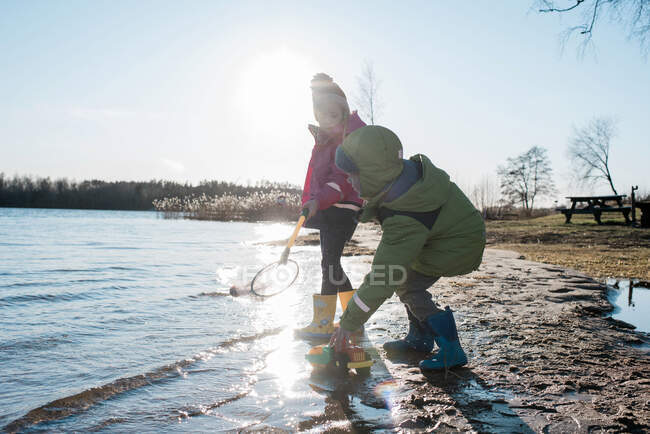 Fratello e sorella giocare con le reti e giocattoli in una spiaggia soleggiata — Foto stock