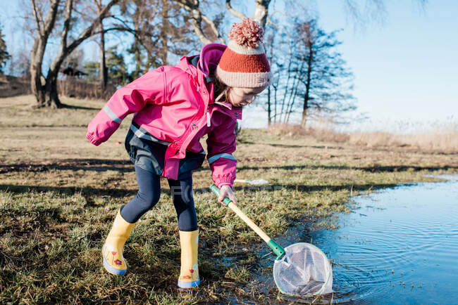 Giovane ragazza che gioca con una rete da pesca in mare in una giornata invernale soleggiata — Foto stock
