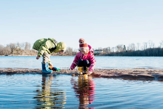 Братья и сестры играют вместе на солнечном пляже зимой в Швеции — стоковое фото