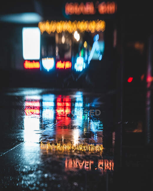 Sinais de néon refletidos em uma poça — Fotografia de Stock