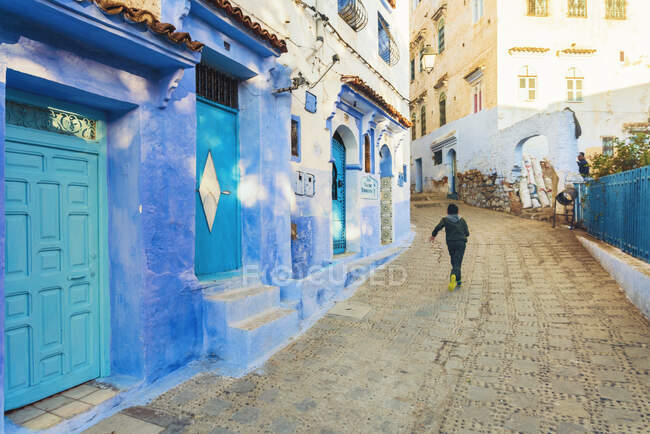 Местный мальчик бежит по улице Chefchaouen голубой деревне — стоковое фото