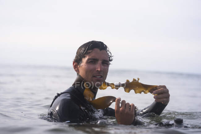 Young Man having fun playing with seaweed — Stock Photo