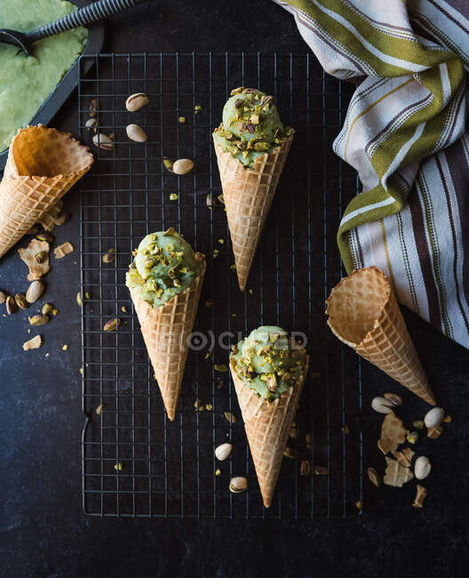 Ice cream in waffle cones with pistachio  on a dark background. top view. — Foto stock