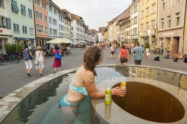 Woman soaks and drinks in outdoor fountain, Winterthur, Switzerland — Stock Photo