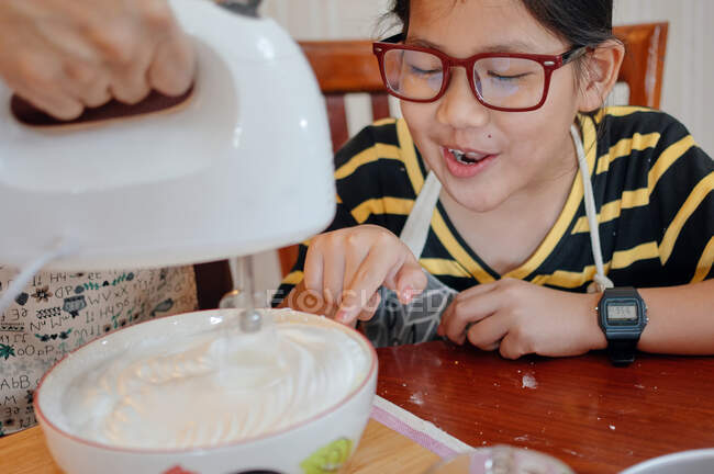 Uma menina estava animada com o merengue durante a mistura — Fotografia de Stock