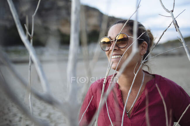 Retrato de una mujer con gafas de sol y sonriendo al atardecer. - foto de stock