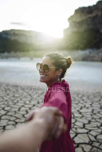 Lächelnde Frau hält ihre Hand für ihren Freund und blickt in die Kamera — Stockfoto
