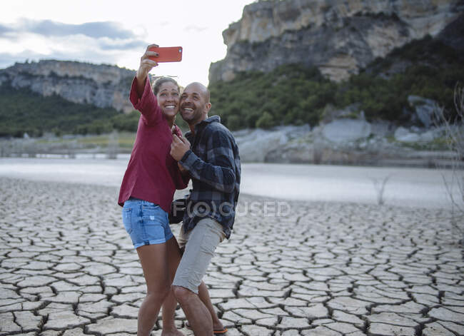 Pareja tomando una selfie en el borde de un lago durante un viaje. - foto de stock