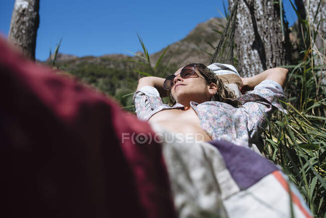 Mujer con gafas de sol tienen un bañosol en la hamaca durante un viaje. - foto de stock
