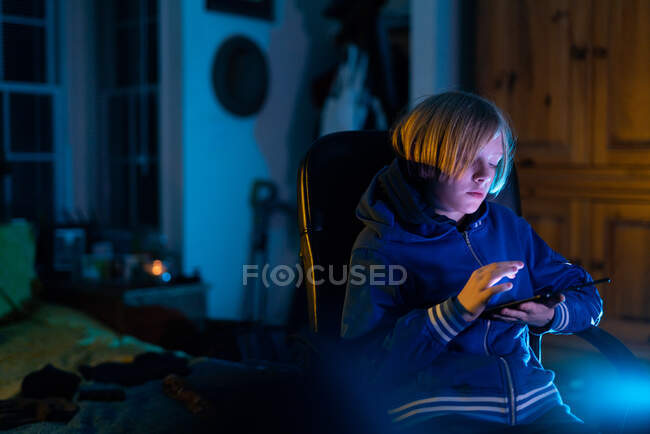 Zwillingsjunge sitzt zu Hause und arbeitet auf Tablet, während er im Stuhl sitzt — Stockfoto