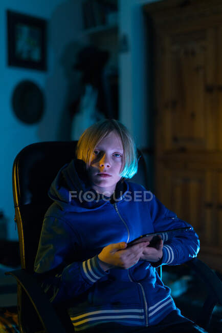 Menino sentado dentro de casa com tablet olhando para a câmera — Fotografia de Stock