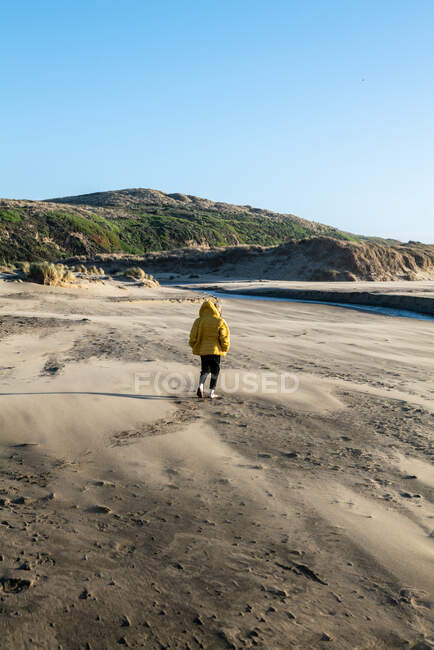 Menino caminha na praia arenosa tword fluxo de água doce levando ao oceano — Fotografia de Stock