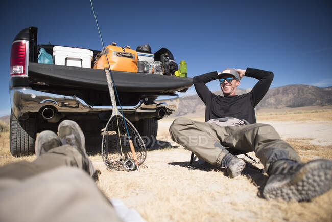 A fly fisherman's relaxes by his tailgate after a day of fishing. — Stock Photo