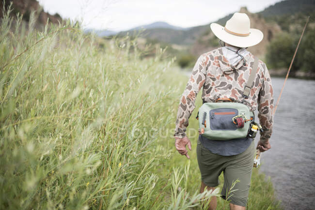A fly fisherman walking up the banks of the Colorado River. — Stock Photo