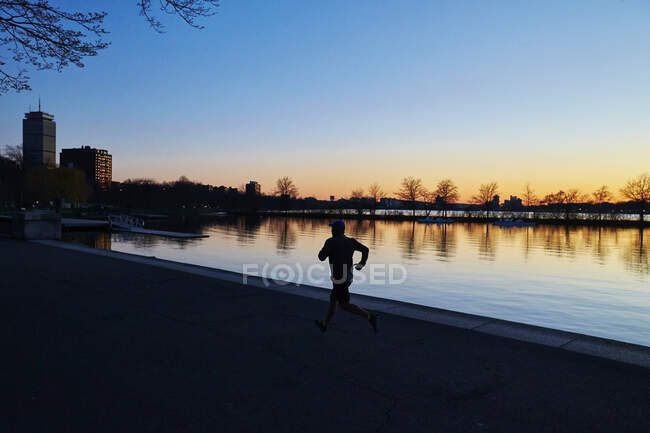 Un uomo al tramonto corre lungo il fiume Charles a Boston. — Foto stock