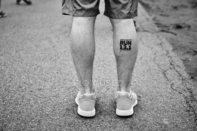 Runner's legs with a half marathon, RUN 13.1, tattoo. — Stock Photo