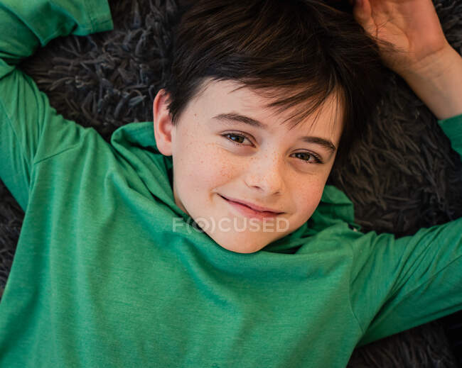 Looking down at the face of a young happy boy laying on a pillow. — Stock Photo