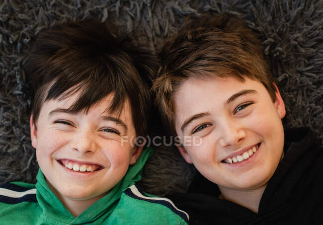 Mirando hacia abajo a las caras de dos chicos uno al lado del otro riendo. - foto de stock