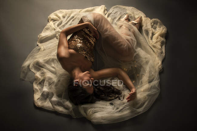 Балерина. Молодой элегантный балетный танцор на полу на вуали — стоковое фото