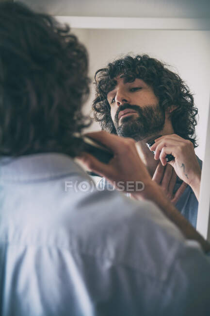 Молодой человек стрижет бороду. Стиль жизни — стоковое фото