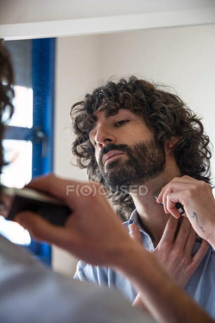 Молодий чоловік обрізає бороду. Стиль життя — стокове фото