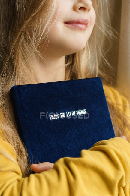 Giovane ragazza che tiene un libro con il testo - godere le piccole cose. — Foto stock