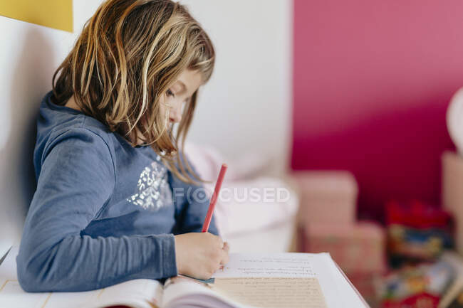 Симпатичная девушка, смотрящая на свою домашнюю работу — стоковое фото