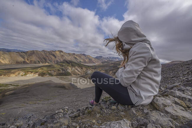 Mujer sonriendo sentada con cámara en el viento, en Landmannalaugar - foto de stock