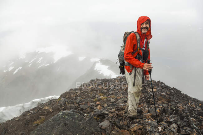 Un hombre está entre las nubes en la cima de la montaña Cooper, en la península de Kenai, Alaska. - foto de stock
