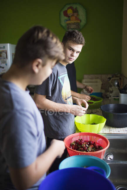 Dos jóvenes preparando comida en la cocina - foto de stock