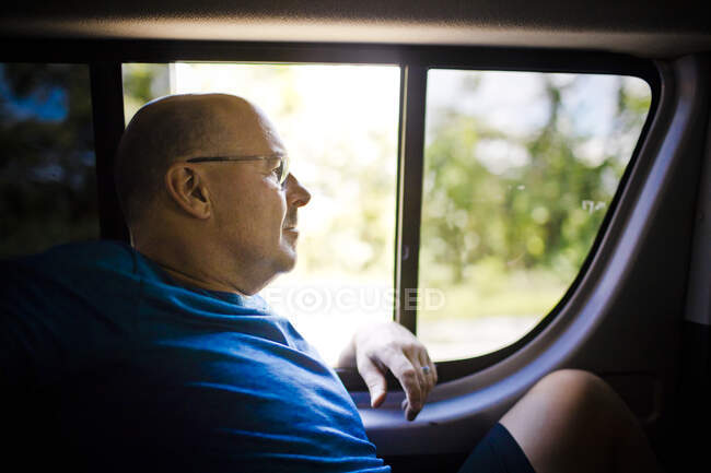 Relaxed retired man sits next to window in back of vehicle. — Stock Photo