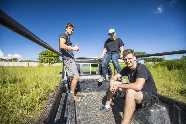 Tre giovani cavalcano attraverso il campo nel retro di un camion 4x4 — Foto stock