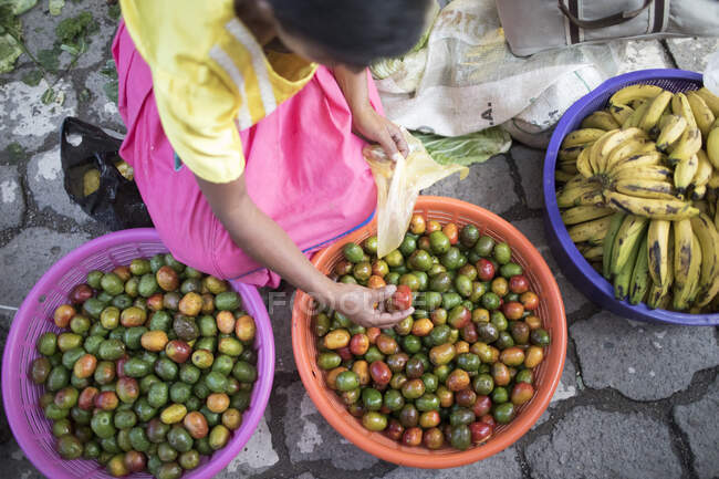 Літня жінка продає органічні фрукти (чокоти) на місцевому ринку. — стокове фото