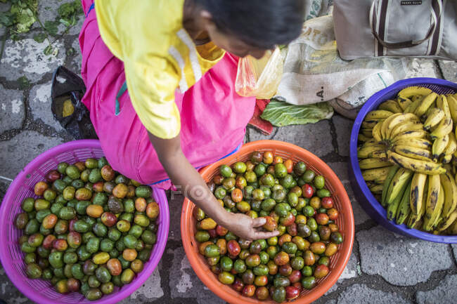 Femme âgée vendant des fruits biologiques (Jocotes) au marché local — Photo de stock