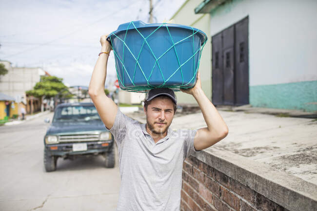 Homem caucasiano carrega cesta em cima de sua cabeça. — Fotografia de Stock