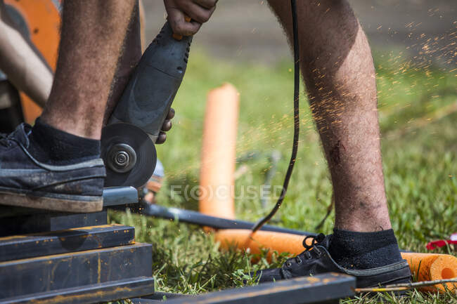 Trabajador que usa amoladora angular para cortar acero. - foto de stock