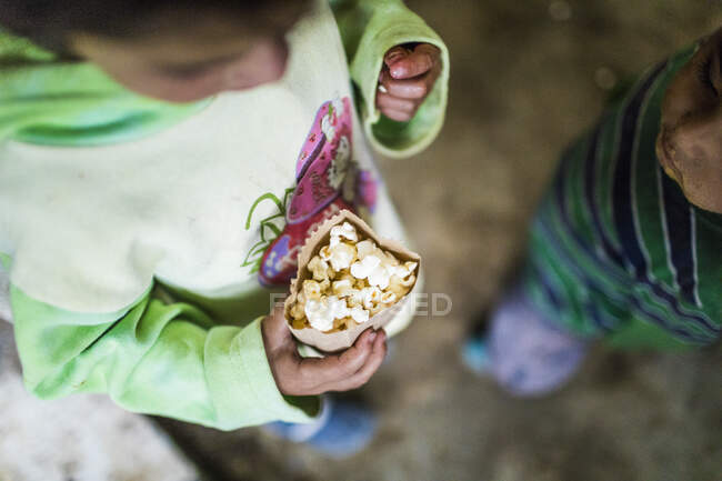Високий кут зору дітей, які їдять попкорн з паперового мішка . — стокове фото