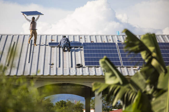 Двоє чоловіків встановлюють стабільні сонячні панелі на даху — стокове фото