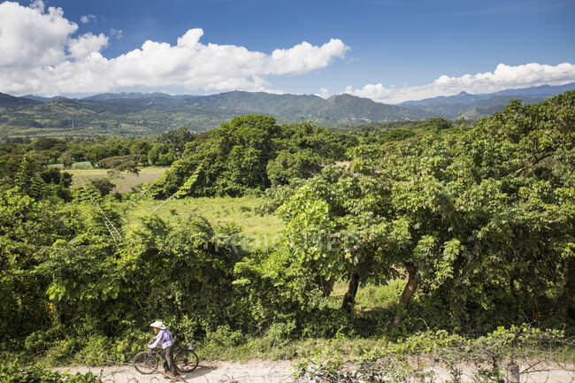 Idoso empurrando bicicleta ao longo da estrada suja na Guatemala — Fotografia de Stock