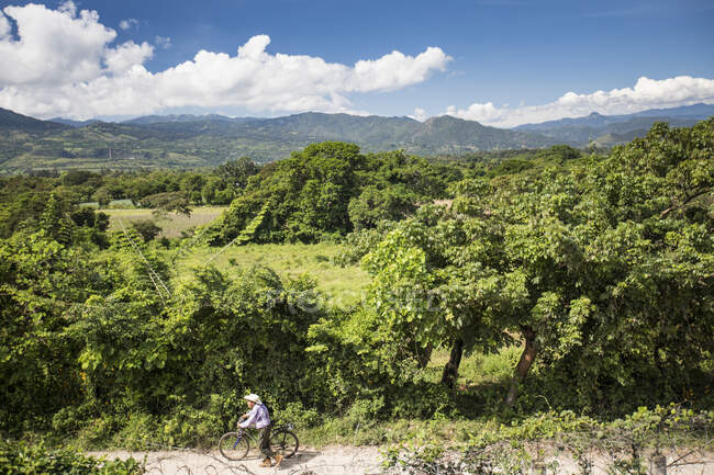 Пожилой человек толкает велосипед вдоль грунтовой дороги, Гватемала. — стоковое фото