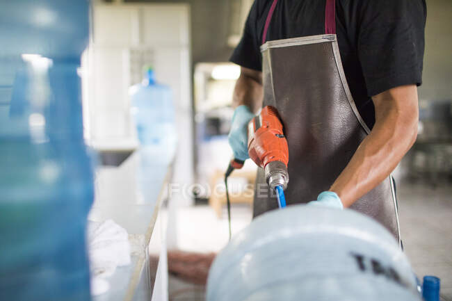 Arbeiter benutzt eine Bohrmaschine, um einen Krug zur Wiederverwendung auszuwaschen — Stockfoto