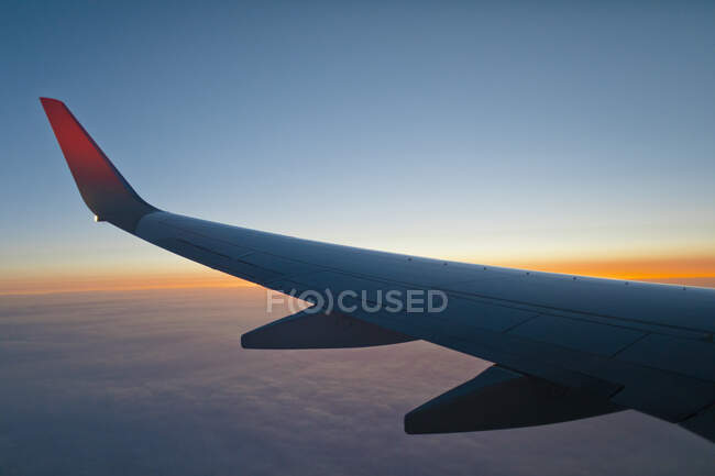 Крило літака середнього повітря на заході сонця, що літає над землею . — стокове фото