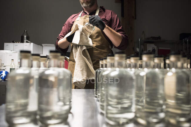 Distiller cleaning of fresh bottles of liquor. — Stock Photo