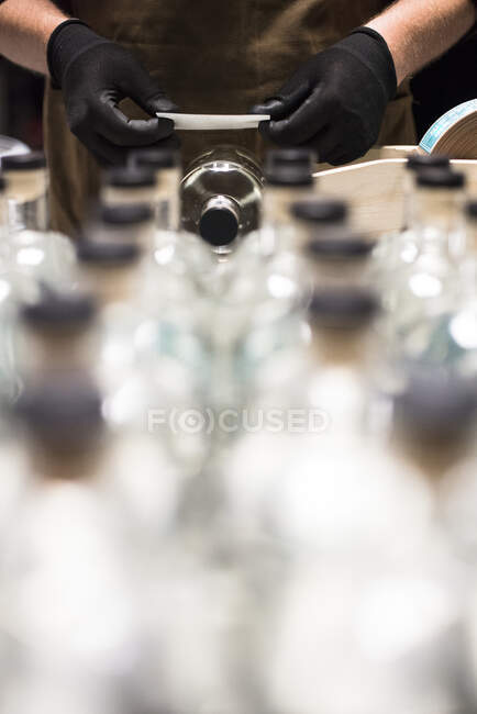 Aplicação de rótulos a garrafas de licor numa destilaria. — Fotografia de Stock