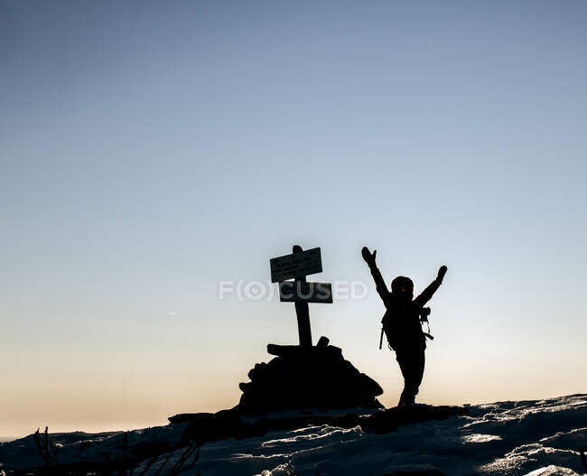 L'escursionista festeggia il raggiungimento della vetta con le braccia alzate la mattina fredda. — Foto stock
