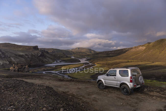 Blick auf geparktes Auto auf Feldweg im Tal mit Fluss und schlängelt sich — Stockfoto